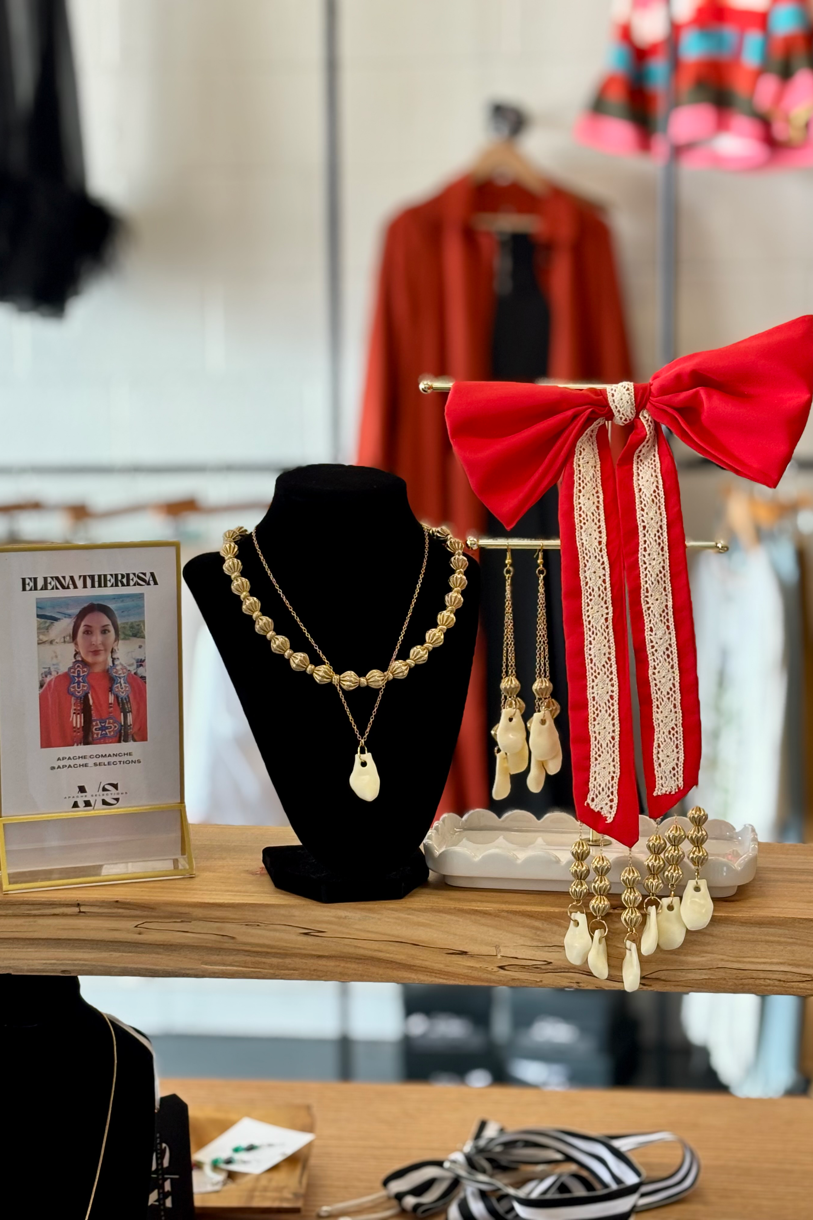 Jewelry display with necklaces and a red bow Cream lace trim, On wooden shelf.